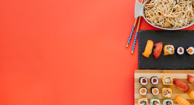 Foto gratuita le bacchette si avvicinano a tagliatelle e sushi su rosso