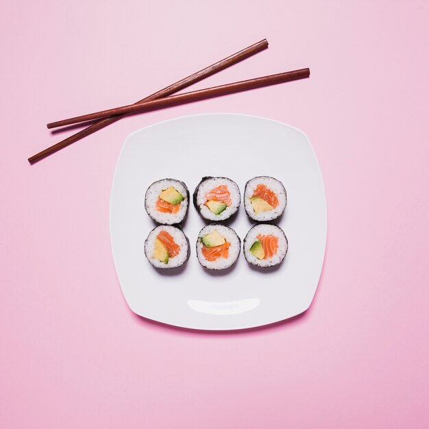 Chopsticks near sushi on pink
