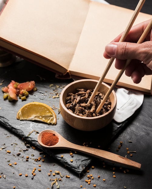 Chopsticks picking larvae from bowl