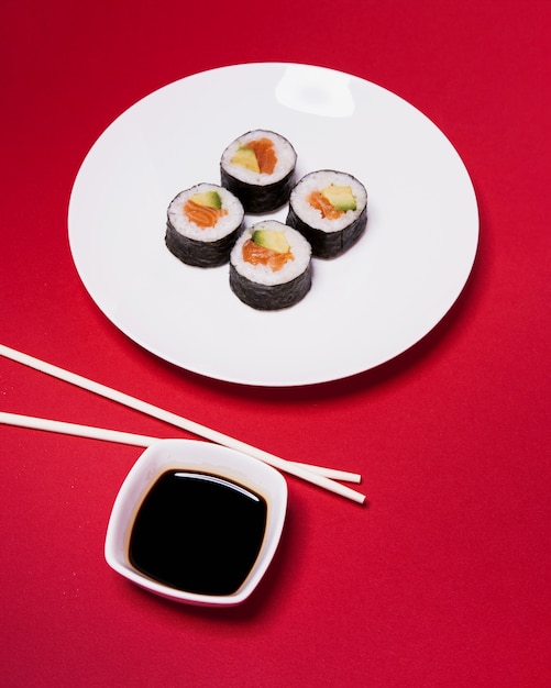 Foto gratuita bacchette e salsa vicino a sushi sul rosso