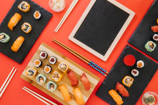 Chopsticks and sushi near chalkboard on red