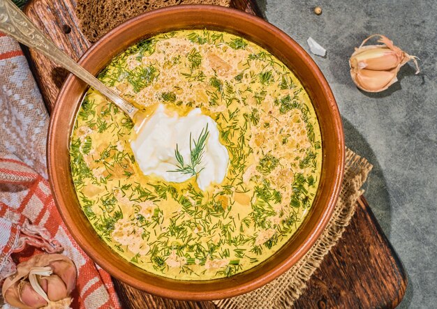 Chowder with vegetables and mushrooms, and chicken meat, layout on a gray background. Served with black bread, sour cream and garlic. A healthy hot winter lunch.