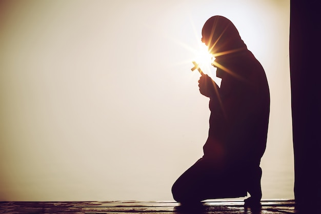 Christian people praying to Jesus christ with dramatic sky background 