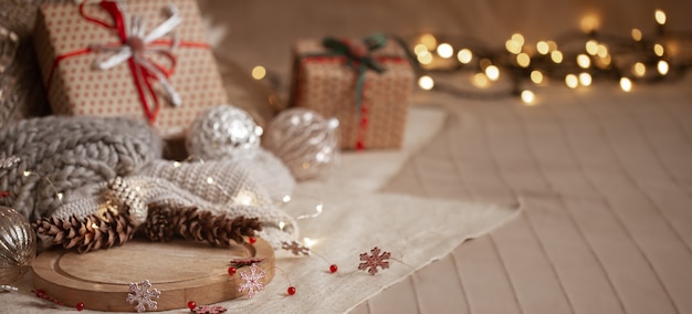 Christmas background composition of pine cones, garlands, gift boxes, home decor details and blurry lights copy space.