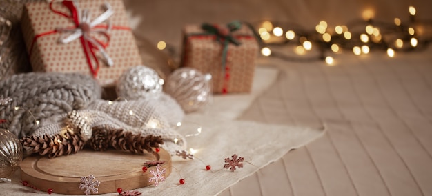 Рождественский фон композиция из сосновых шишек, гирлянд, подарочных коробок, деталей домашнего декора и размытых огней копирует пространство.
