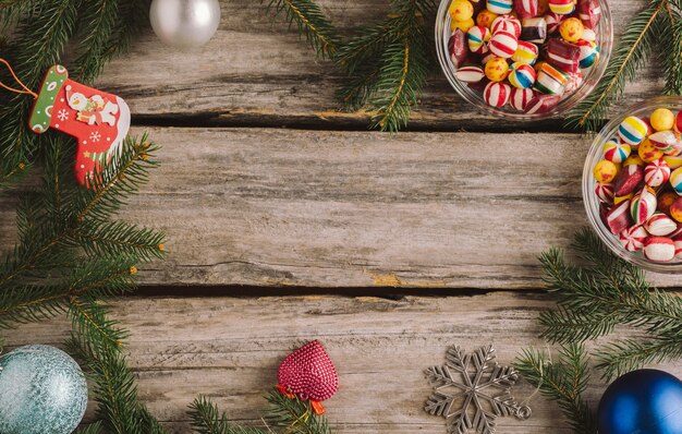 Christmas background with baubles and spruce tree branches on a wooden surface