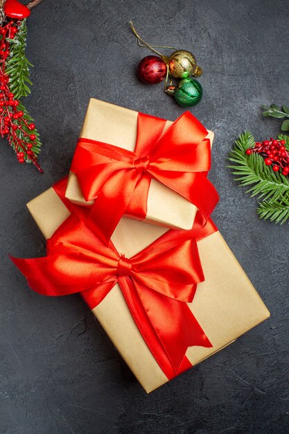 Christmas background with beautiful gifts with bow-shaped ribbon and fir branches decoration accessories on a dark table above view