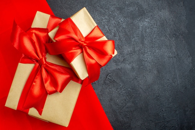 Christmas background with beautiful gifts with bow-shaped ribbon on a red towel on a dark background