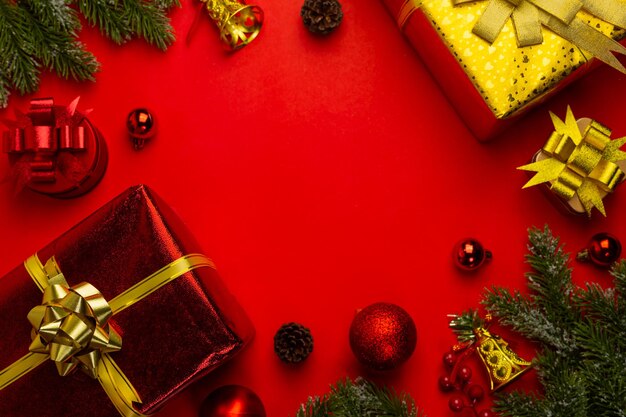 빨간 배경에 전나무 가지, 선물 또는 선물, 빨간 공이 있는 크리스마스 배경. 복사 공간이 있는 상위 뷰