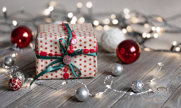 Christmas background with gift box close up on wooden surface, Christmas balls and bokeh lights, copy space.