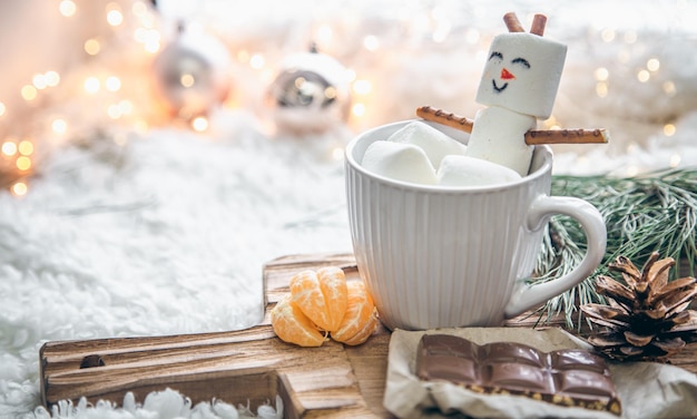 カップにマシュマロ雪だるまとクリスマスの背景