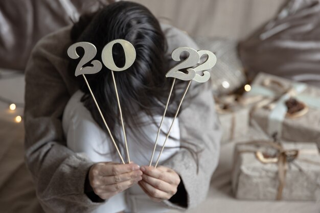 Christmas background with wooden numbers 2022 on sticks in female hands
