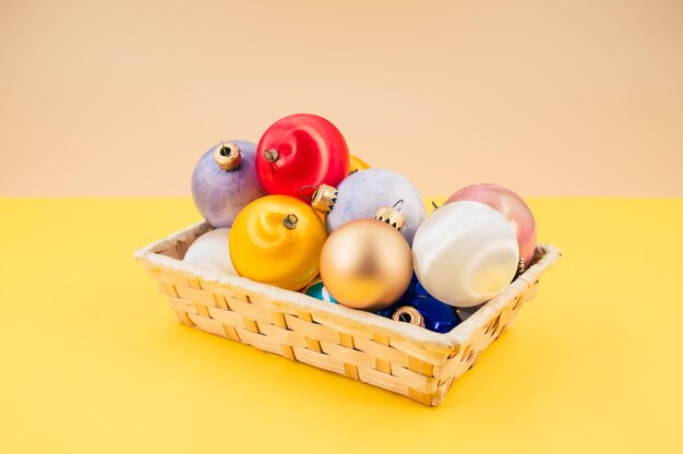 Christmas ball decorations in a basket on yellow background