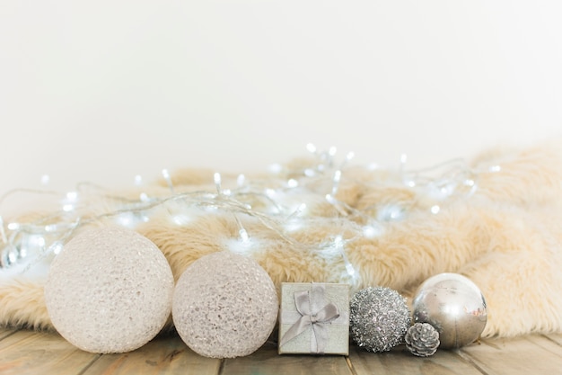 Christmas balls near fairy lights and coverlet