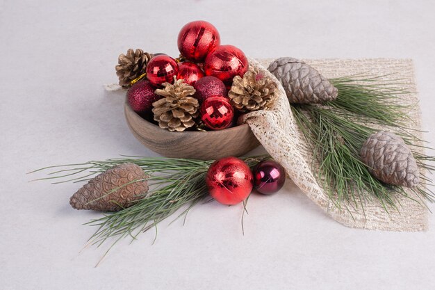 Christmas balls and pinecone on white surface