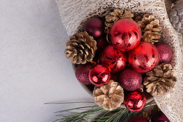 Christmas balls and pinecone on white table.