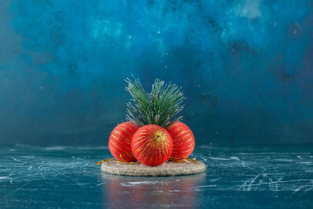 Christmas baubles arranged on a trivet on marble.