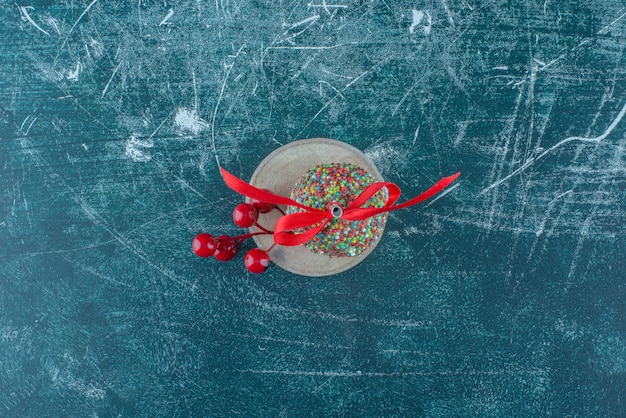Рождественские ягоды орнамент и леденец на куске дерева на синем фоне. Фото высокого качества