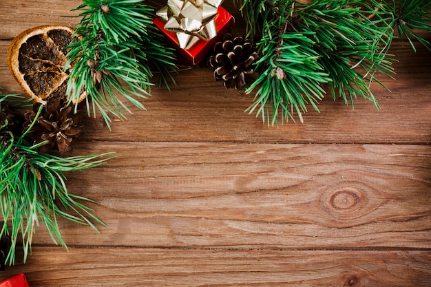 Christmas branch with little box on wooden board