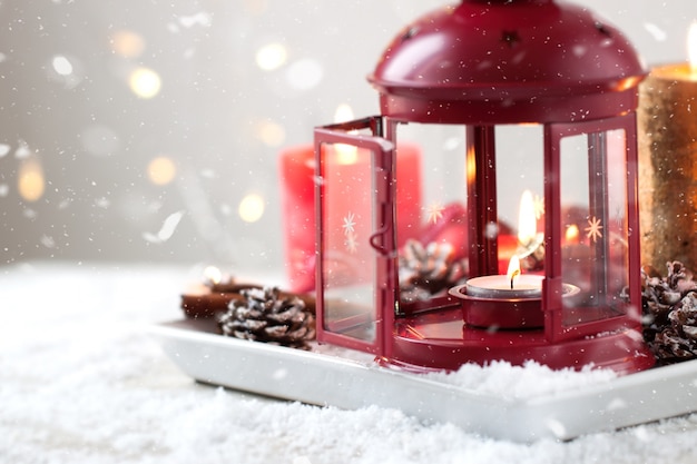 Christmas candles with fir cones, lantern, christmas decoration and snow, winter or holiday concept