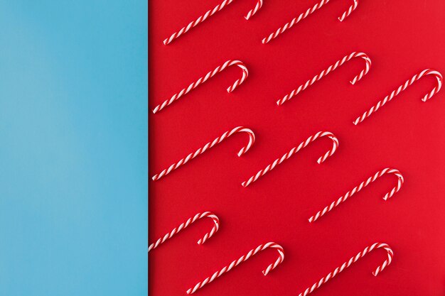 Christmas candy cane on red paper background top view