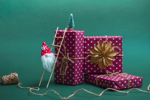 クリスマスカード​の​モックアップ​。​緑​の​背景​に​贈り物​の​山​と​階段​に​ノーム​。​コピー​スペース​を​閉じる