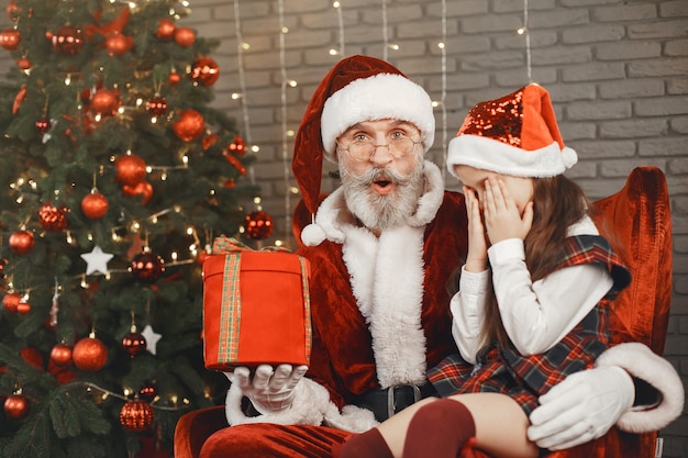 Christmas, child and gifts. Santa Claus brought gifts to kid. Joyful little girl hugging Santa.