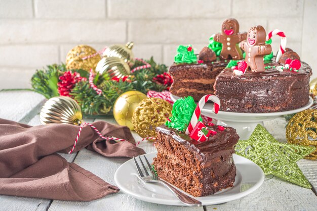 クリスマスチョコレートケーキ。クリスマスの伝統的なシンボルの形で砂糖とチョコレートの装飾が施された自家製ジンジャーブレッドチョコレートケーキ-キャンディケイン、ジンジャーブレッドマン、クリスマスツリー、