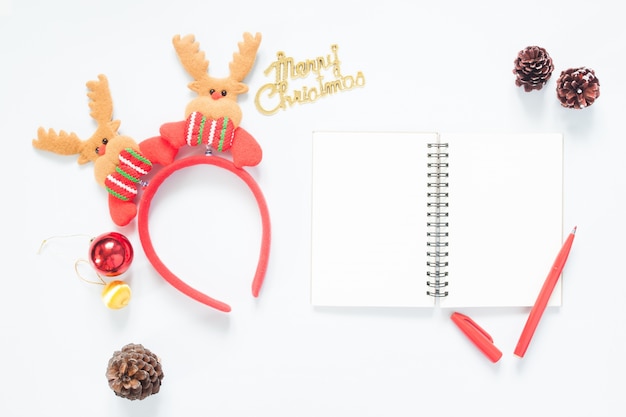 クリスマスの組成。クリスマスの装飾、松のコーン、ノートブック、コピースペースのある赤いペン。フラットレイ、トップビュー