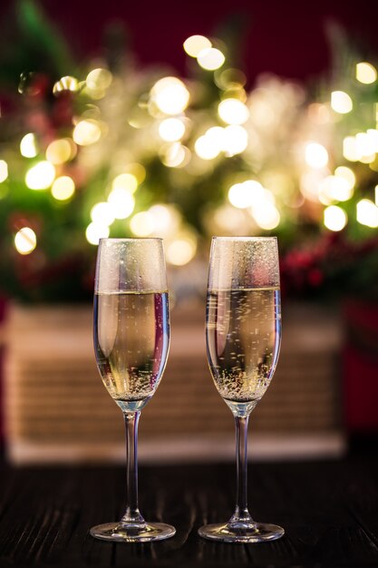 Christmas composition christmas trees decorated with golden lights, garlands, toys and empty champagne glasses.