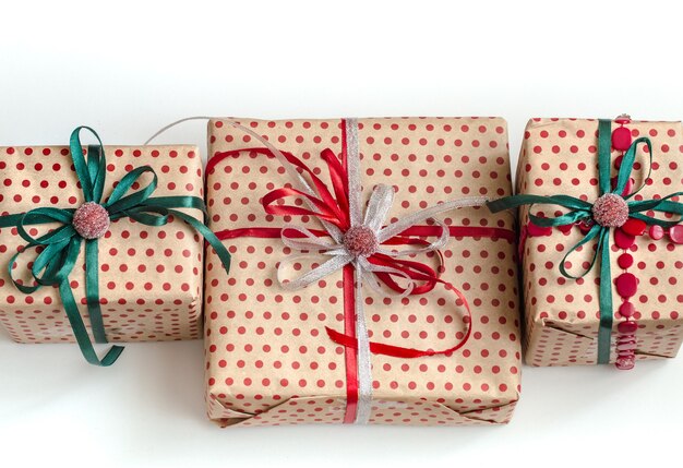 Christmas composition of various gift boxes wrapped in craft paper and decorated with satin ribbons. Top view, flat lay. White wall.