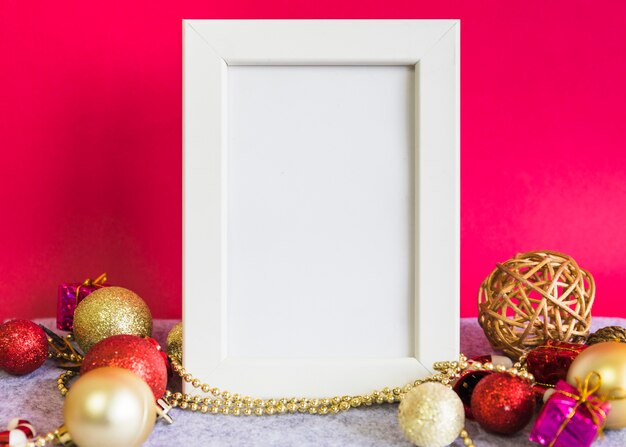 Christmas composition of white frame with baubles on table
