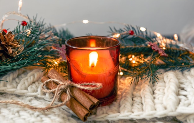 Free photo christmas composition with candle and cinnamon sticks on blurred background