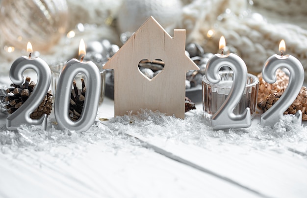 Christmas composition with candles in the shape of the numbers 2022 and festive decor details on a blurred background.