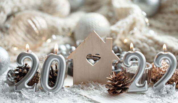 Christmas composition with candles in the shape of the numbers 2022 and festive decor details on a blurred background.