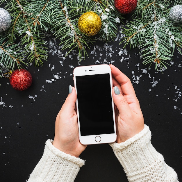 Foto gratuita composizione di natale con le mani che tengono smartphone