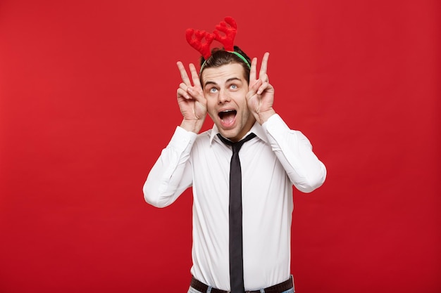Free photo christmas concept handsome business man celebrate merry christmas and happy new year wear reindeer hairband and holding rabbit gesture