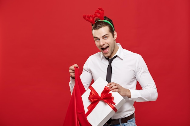 Concetto di natale l'uomo d'affari bello celebra il buon natale e il felice anno nuovo indossa una fascia per capelli con renne che tiene la borsa grande rossa di babbo natale