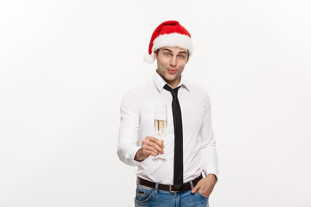 クリスマスのコンセプトハンサムなビジネスマンはメリークリスマスを祝い、新年あけましておめでとうございますシャンパングラスでサンタの帽子をかぶる
