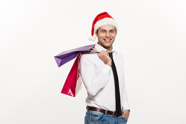 크리스마스 컨셉의 잘생긴 사업가는 메리 크리스마스를 축하하고 새해 복 많이 받으세요 산타 모자를 쓰고 산타 빨간 큰 가방을 들고