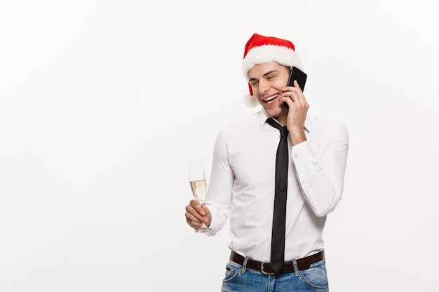 クリスマスのコンセプトハンサムなビジネスマンが電話で話し、chirstmasと新年を祝うシャンパングラスを持っています 無料写真