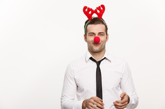 Free photo christmas concept handsome business man wearing reindeer hairband making funny facial expression