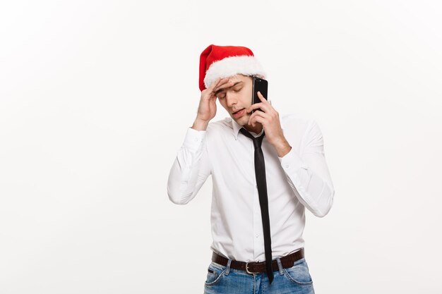 クリスマスのコンセプトストレスの多いハンサムなビジネスマンはクリスマスの日に電話で真剣に話します