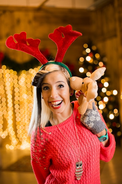 Christmas concept with joyful woman holding toy reindeer