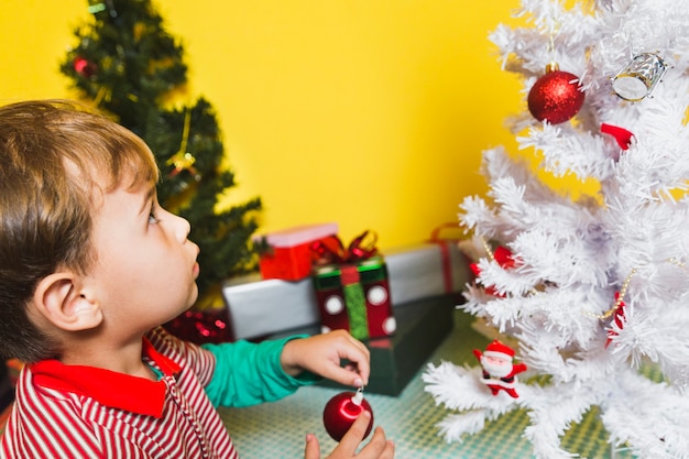 Free photo christmas concept with kid looking at christmas tree