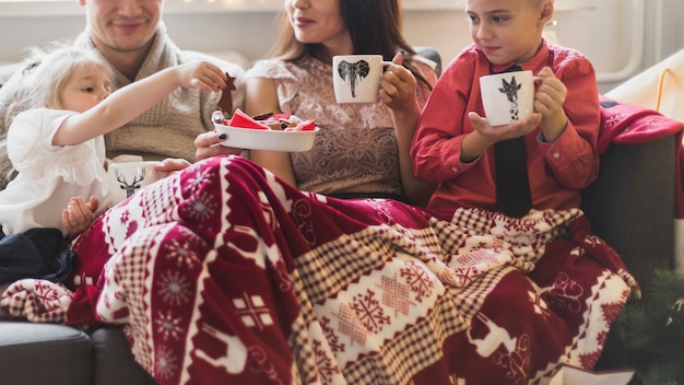 Concetto di natale con la giovane famiglia bere il tè