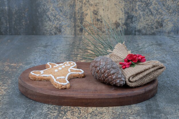 Christmas cookie with pinecone on wooden board. 