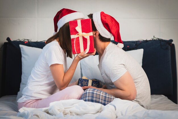 Christmas couple hiding behind gift