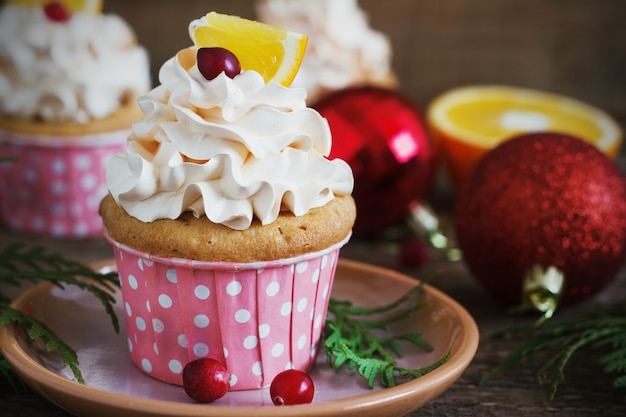 ホイップクリーム​の​トッピング​と​クランベリー​、​オレンジ​の​クリスマスカップケーキ​。​お祝い​食品​の​デザート​。