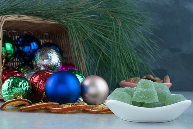 Рождественские праздничные шары с белой тарелкой, полной зеленого мармелада. Фото высокого качества